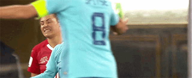 a soccer player wearing a blue shirt with the number 8 on it is standing next to another player .