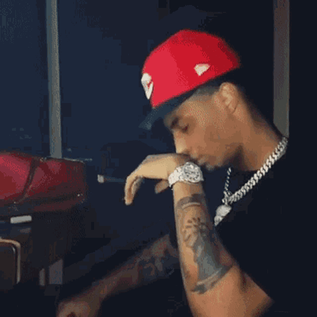 a man in a red hat is smoking a cigarette .