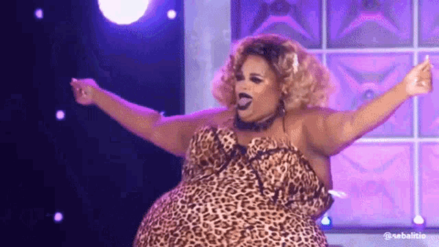 a drag queen wearing a leopard print dress is dancing on a stage .