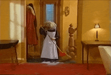 a woman in an apron is sweeping the floor with a red broom