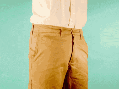 a man in a white shirt and tan pants holds his hand in his pocket