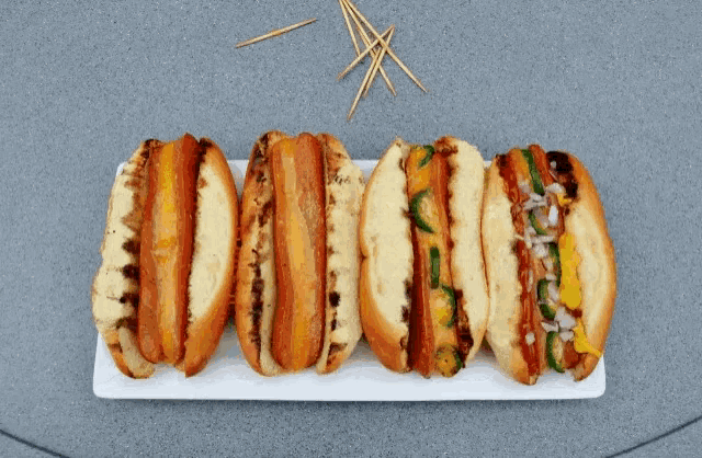 a bunch of hot dogs on a plate with toothpicks in the background