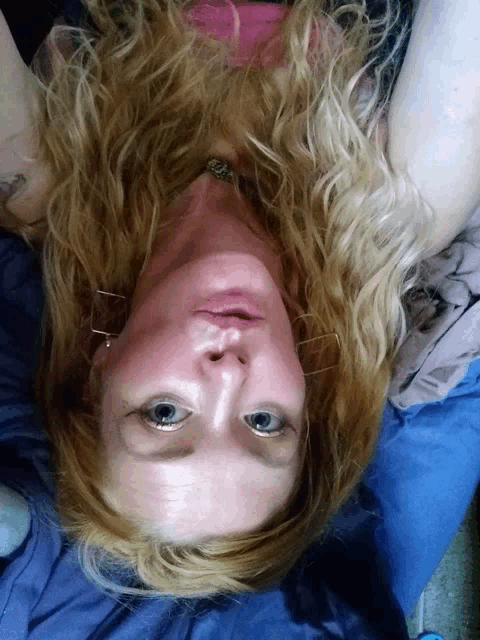 a woman with blonde hair and blue eyes laying on her back