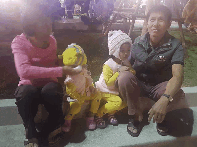 a man wearing a jacket that says always sits next to a woman and two children