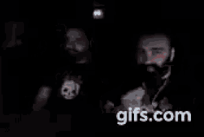 a blurry picture of two men standing next to each other in a dark room .