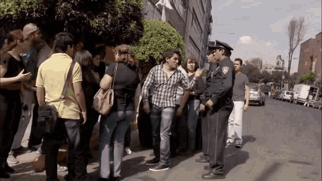 a group of people standing on a sidewalk with a police officer