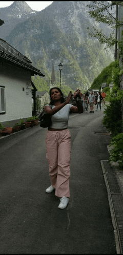 a woman taking a picture of a mountain while standing on a street
