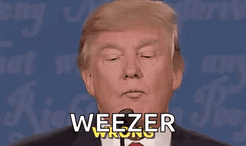 a man in a suit and tie is talking into a microphone and the words weezer wrong are on his face .