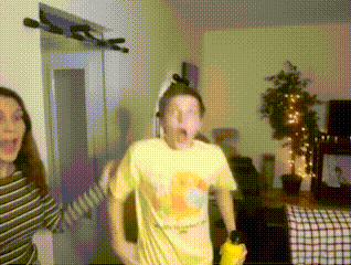 a man in a yellow shirt is dancing with a woman in a striped shirt in a living room .