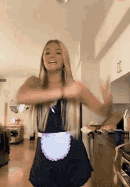 a woman in a maid costume is dancing in the kitchen .