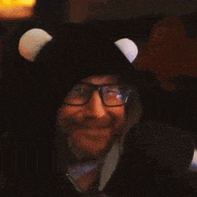 a man wearing glasses and a black hat with white ears is giving an ok sign