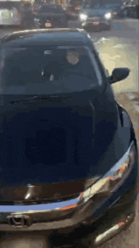 a man is driving a black honda car on a street