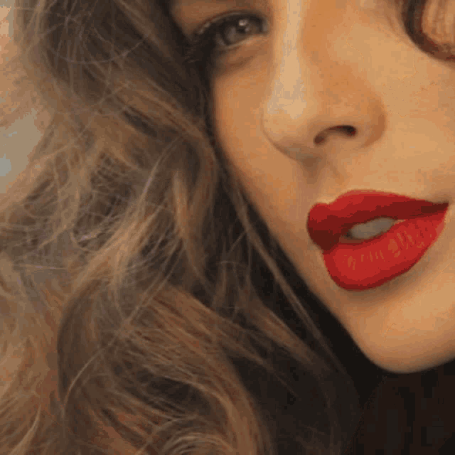 a close up of a woman 's face with red lipstick on her lips