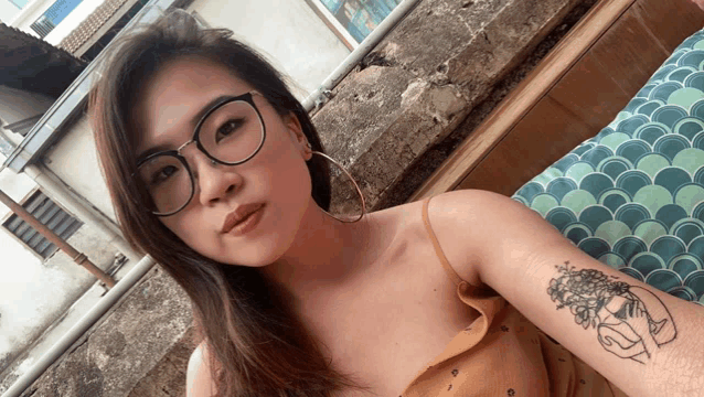 a woman wearing glasses has a tattoo on her arm that says " i love you "