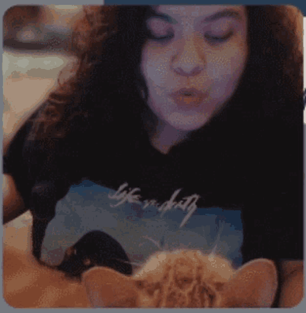 a woman wearing a black shirt that says life is duty kisses a cat