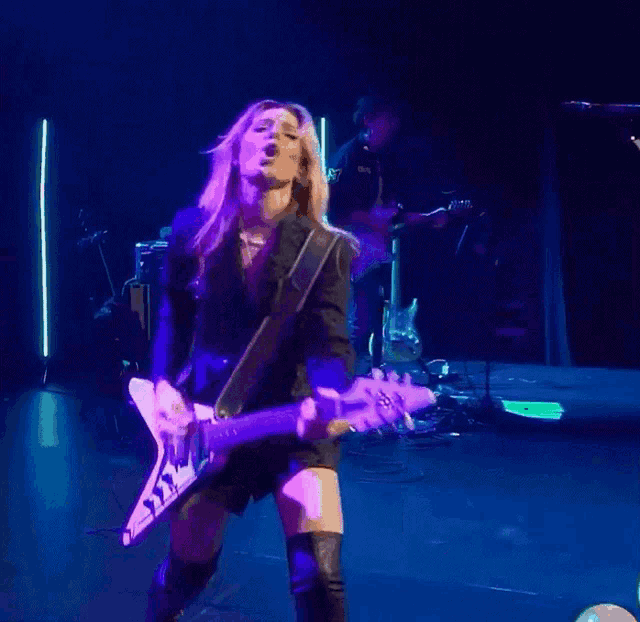 a woman is playing a guitar and singing on stage