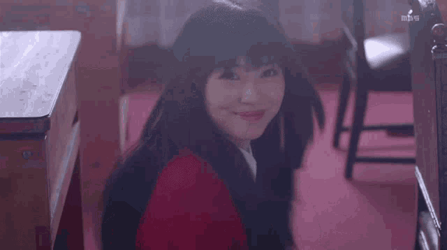 a woman in a red jacket is waving her hands in a room