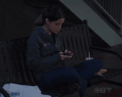a woman sitting on a bench looking at her phone