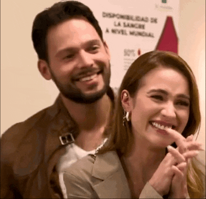 a man and a woman are laughing together in front of a sign .