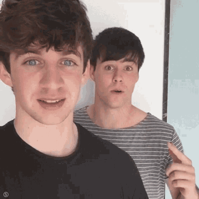 two young men are standing next to each other and one of them is pointing