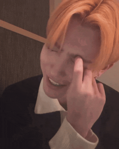 a man with red hair is making a heart with his hand