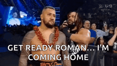 two men are standing next to each other in a wrestling ring and one of them is talking to the other .