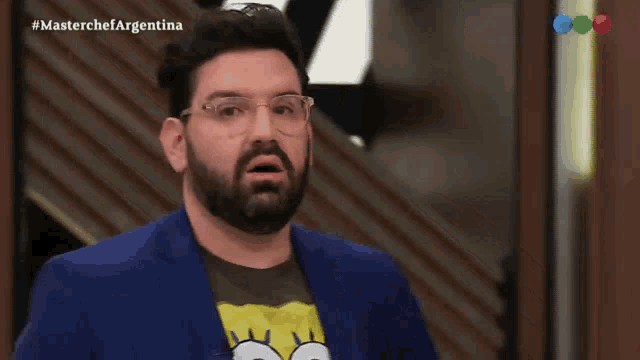a man wearing a spongebob shirt and a blue suit is covering his face with his hand