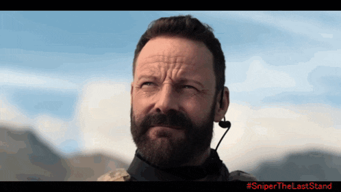 a man with a beard is wearing a headset with the hashtag #sniperthelaststand on it