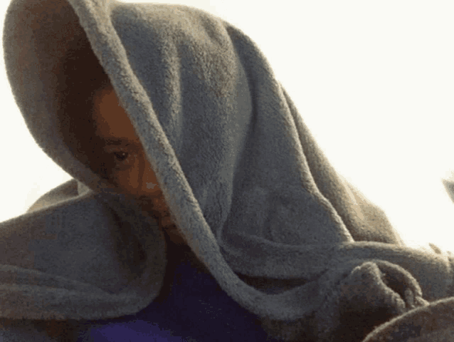 a person covered in a blue blanket with their eyes visible