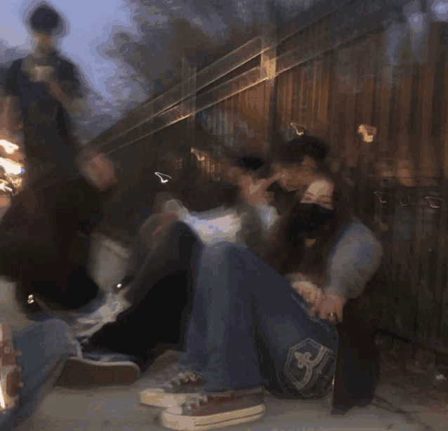a blurry photo of a group of people sitting on a sidewalk