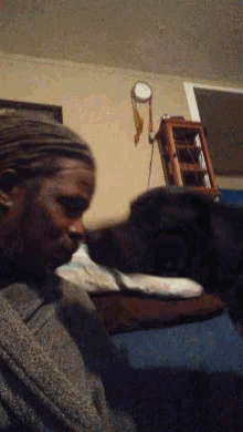 a man is sitting on a couch with a dog licking his face