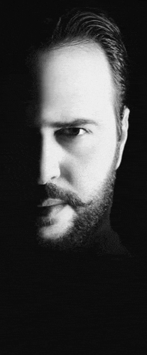 a man with a beard and mustache is wearing a black turtleneck .