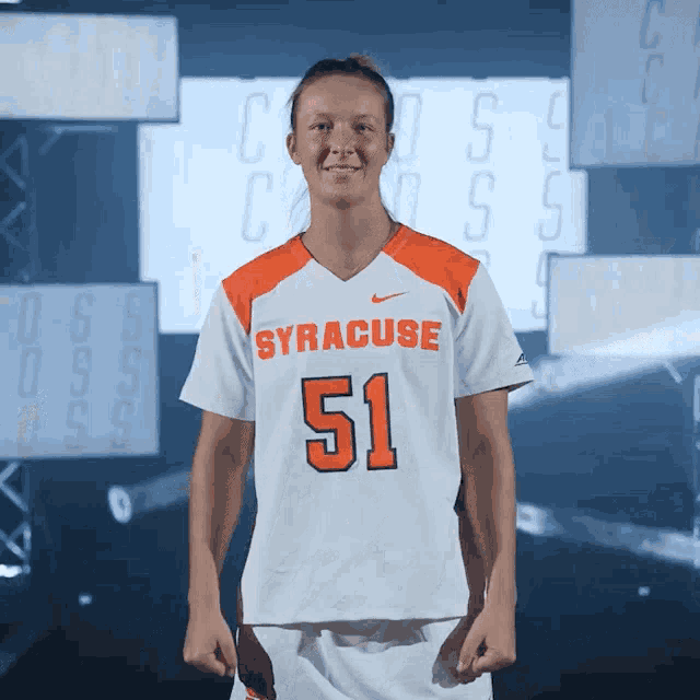 a woman wearing a white and orange syracuse jersey