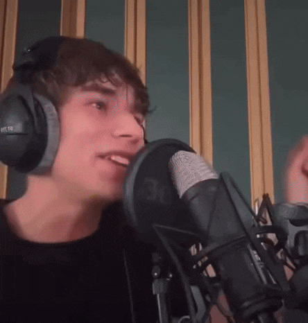 a young man wearing headphones is singing into a microphone with the number 30 on it .