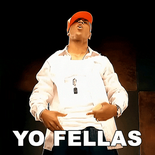a man wearing an orange hat is standing in front of a sign that says yo fellas on it