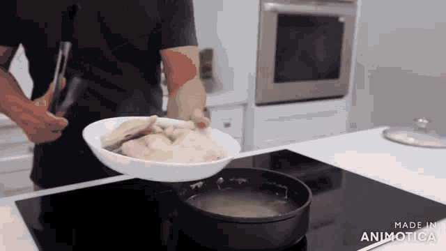 a man is putting chicken into a pot of water on a stove .