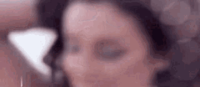 a close up of a woman 's face with her eyes closed and a blurry background .