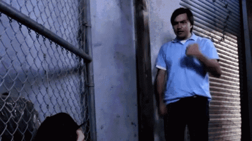 a man in a blue shirt is talking to another man