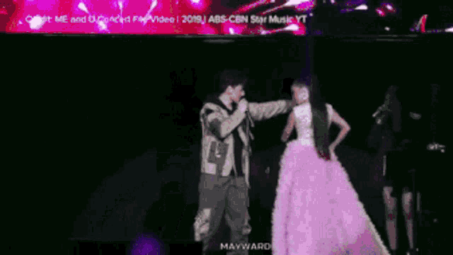 a woman in a pink dress is dancing with a man in a microphone
