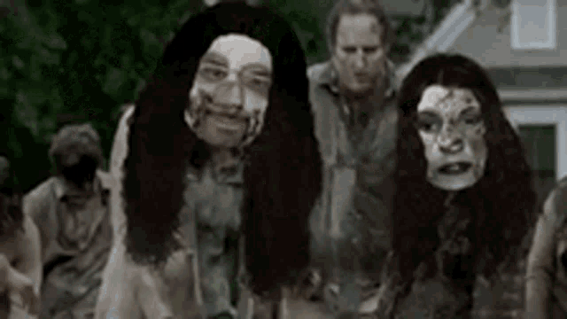 a group of zombies are standing next to each other in front of a house .