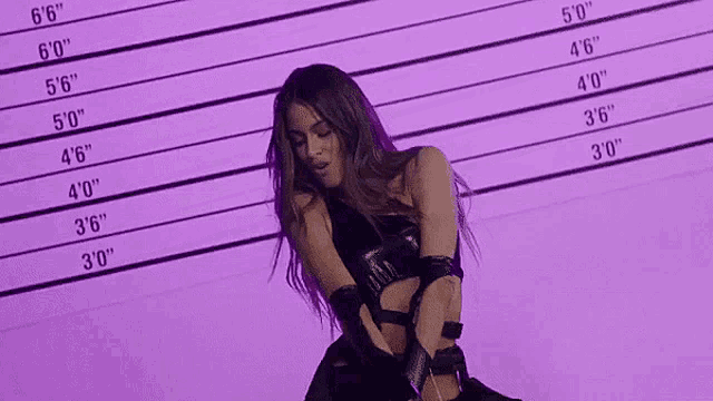 a woman in a black dress is standing in front of a purple background with a police line .