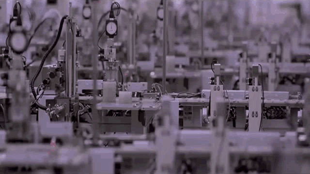 a factory with a lot of machinery and a clock on the top of one of the machines .