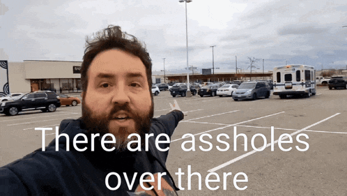 a man stands in a parking lot with the words there are assholes over there