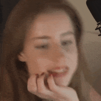 a close up of a woman 's face with her hand on her chin and a microphone in the background .