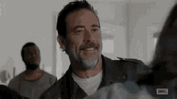a man with a beard is smiling at a woman in a room .
