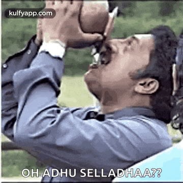 a man is drinking from a glass while holding a football in his hands .