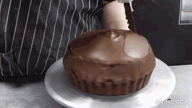 a giant chocolate cupcake is being decorated by a person with a knife