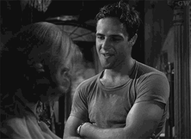 a black and white photo of a man talking to another man .