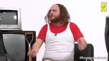 a man with a beard is sitting in front of a television .