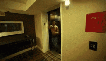 a man without a shirt is standing in an elevator in a room